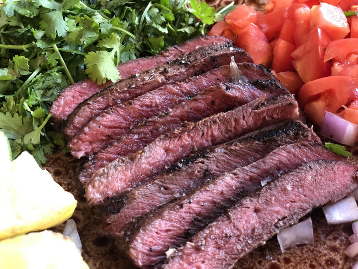 Flat iron steak cut up, ready to be put into a taco / fajita with diced tomato and cilantro