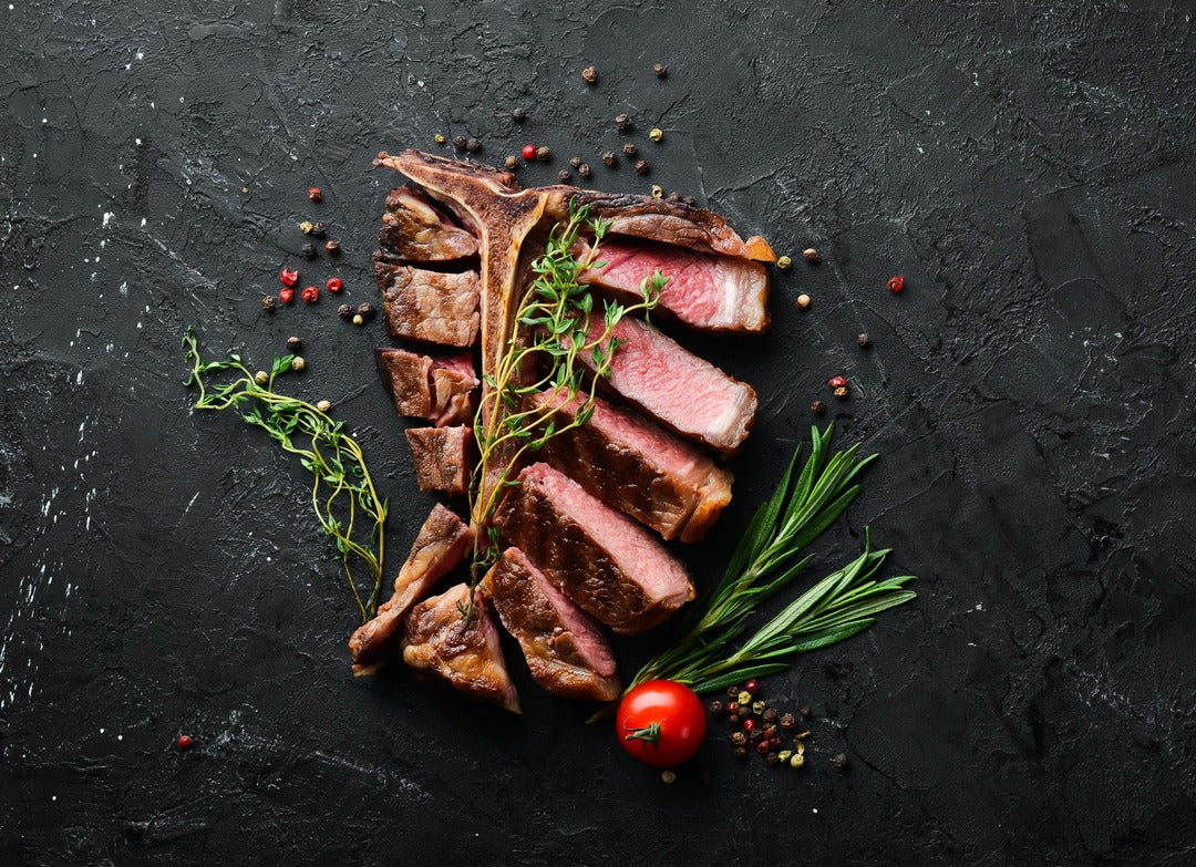 Beatifully cooked and cut medium rare t-bone with rosemary and thyme aromatics