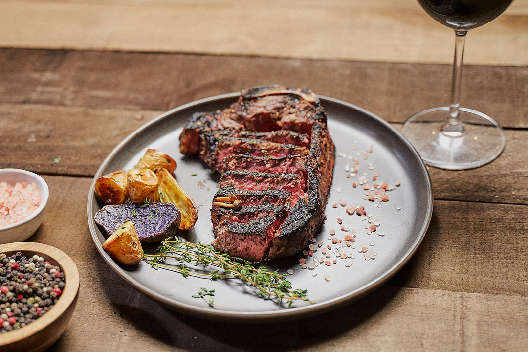 Stunning plating of a bone-in New York Strip with salt, thyme, and potatoes on the side